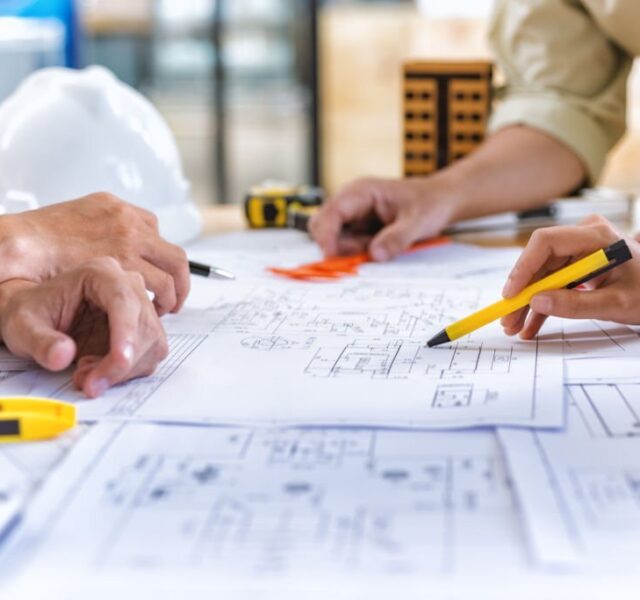 Image of team engineer checks construction blueprints on new project with engineering tools at desk in office.